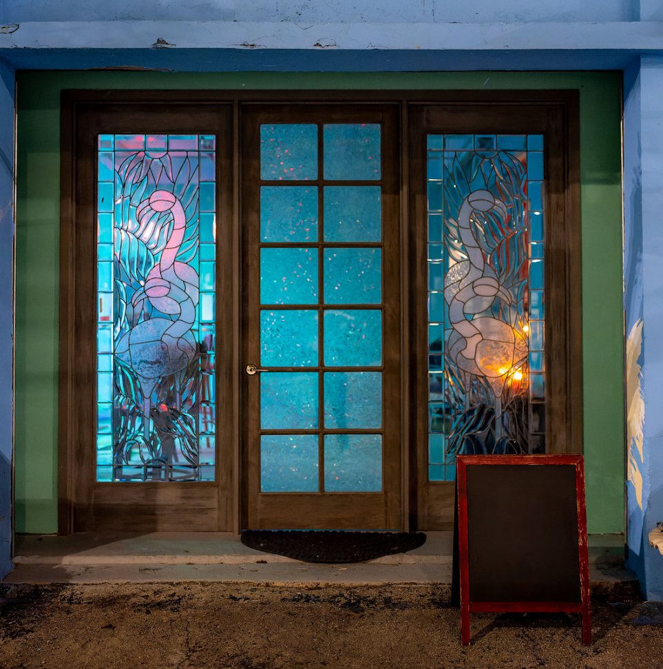 Dear Eleanor's glowing front doors with stained-glass flamingos